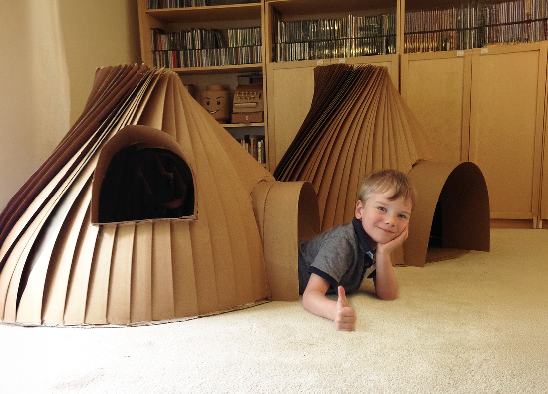 Kid hanging in one of two igloos made from cardboard