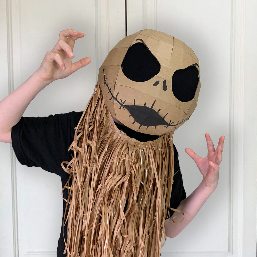 Person wearing a Cardboard Jack Skellington inspired mask with long hair against a white door background