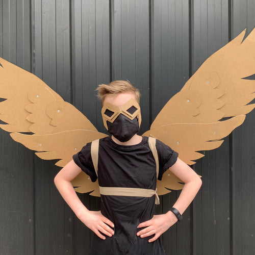 Person wearing a black costume with cardboard wings against a dark background