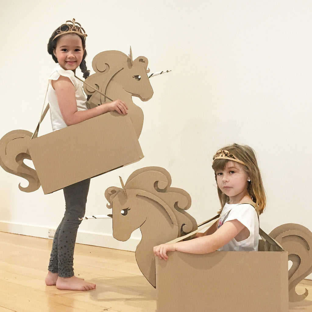 Two children playing with cardboard unicorn box costumes.