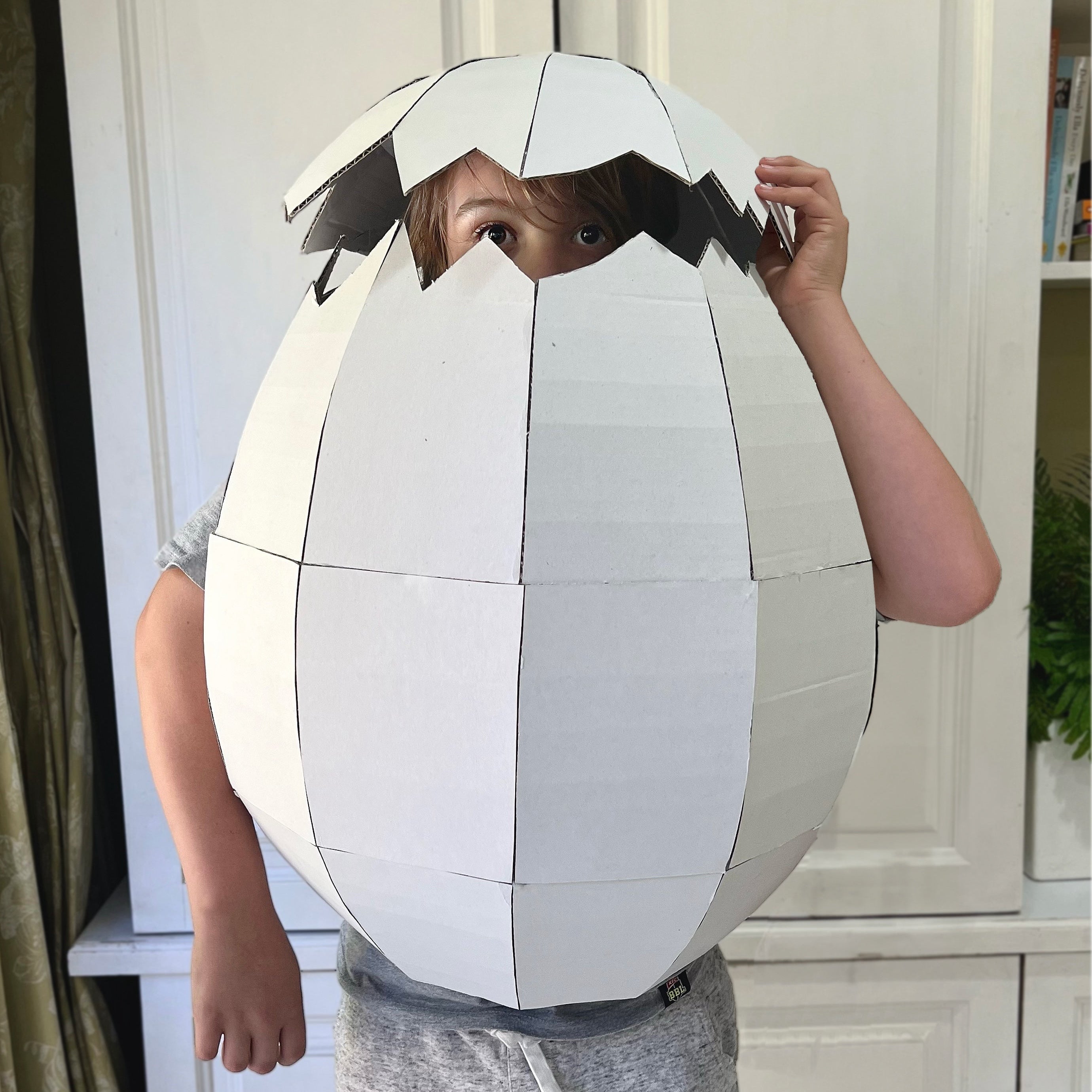 Person wearing a large white egg-shaped costume indoors.