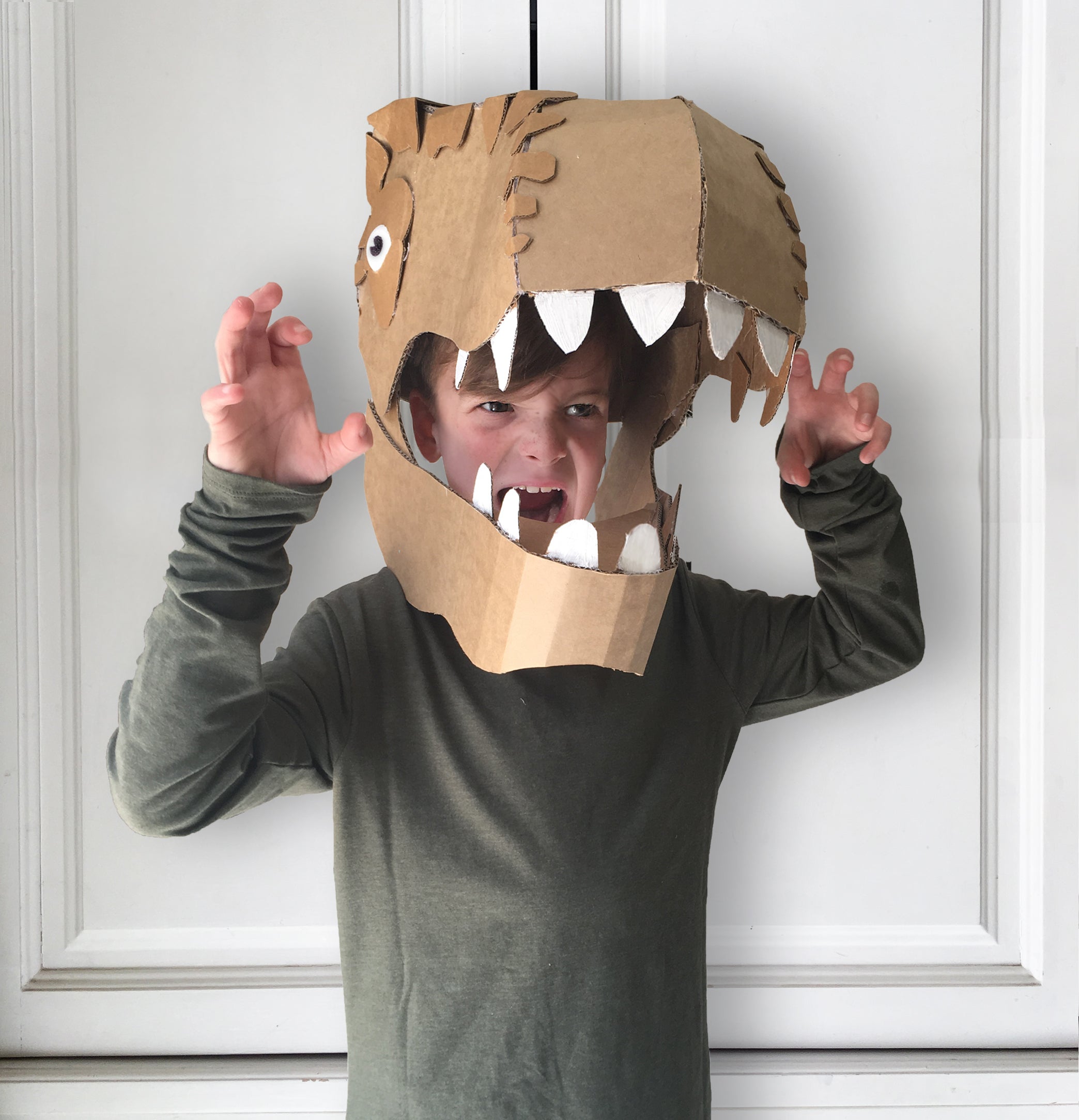 Child roaring in a Dinosaur head costume made from cardboard